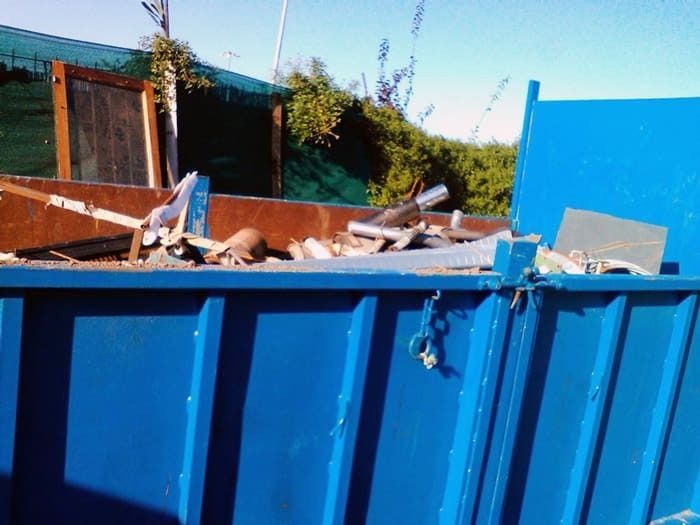 Un contenedor azul con un montón de basura dentro