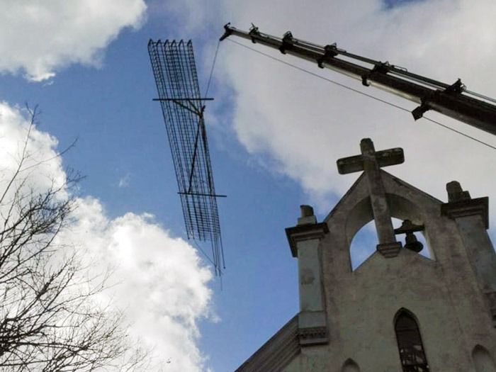 Una grúa está levantando una gran estructura metálica sobre una iglesia.