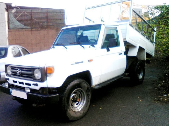 Una camioneta Toyota blanca está estacionada al costado de la carretera.
