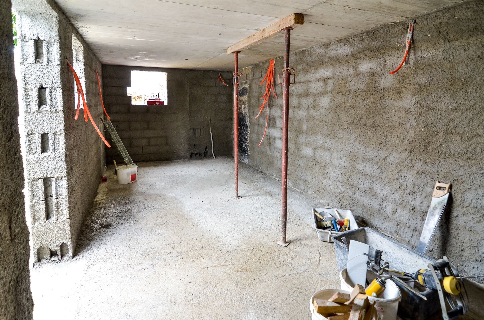 Pièce inachevée en construction, avec murs apparents, fils électriques et matériaux de construction.