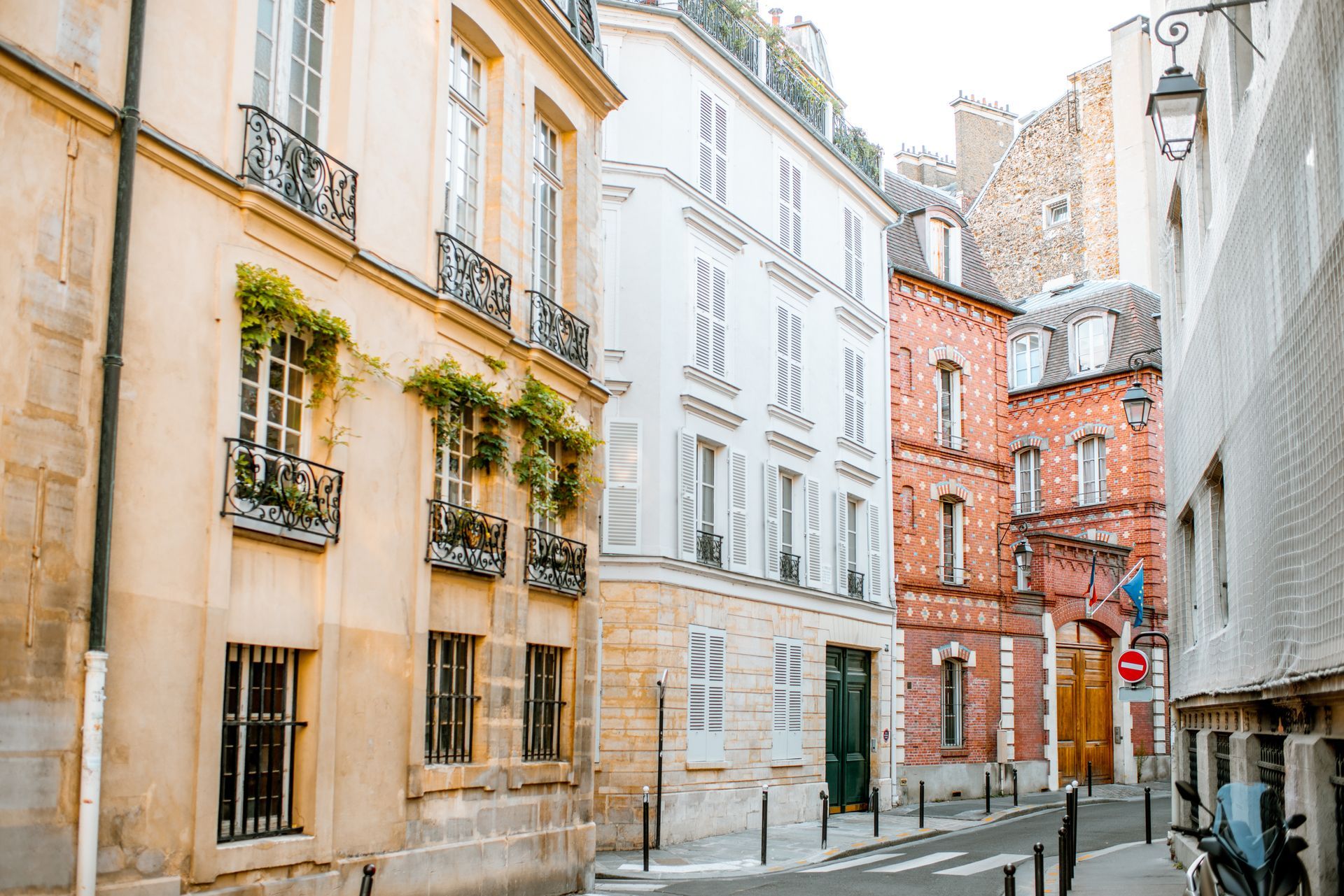 Rue étroite bordée de vieux bâtiments aux teintes pastel et d'une maison d'angle en briques rouges
