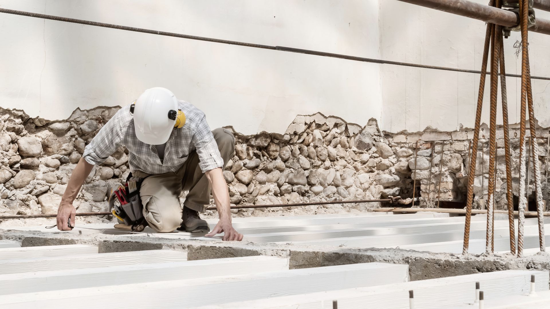 Ouvrier du bâtiment qui mesure des fondations sur un chantier