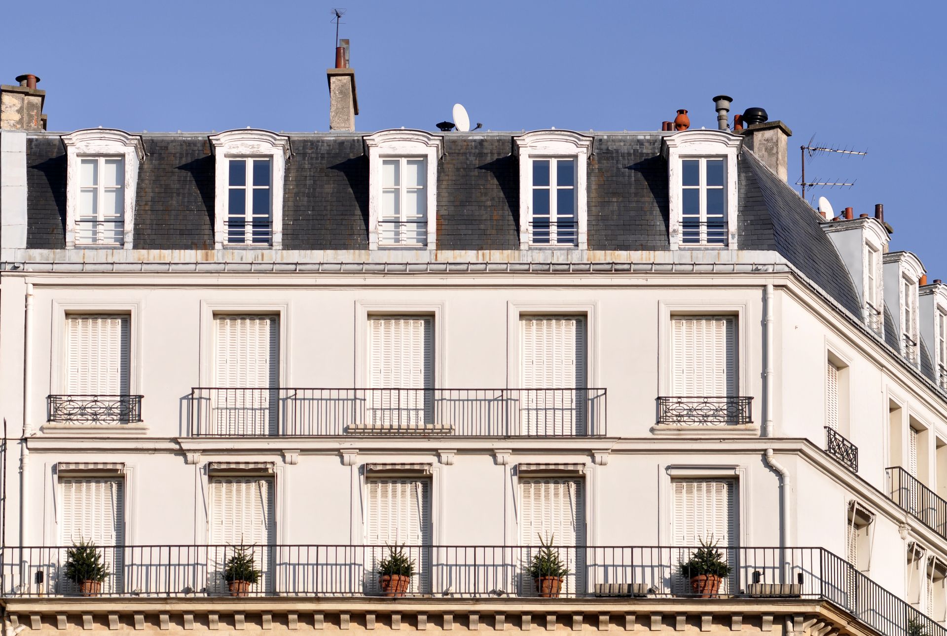 Immeuble d'appartements parisien avec toit mansardé noir sous un ciel bleu