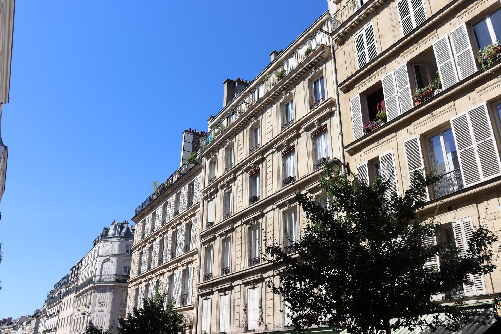 Immeubles d'appartements parisiens bordant une rue sous un ciel bleu clair
