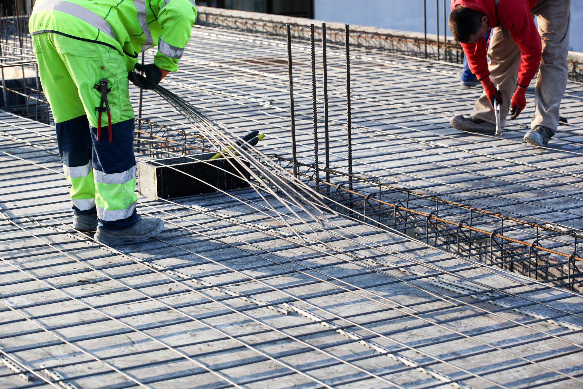 Des ouvriers du bâtiment placent des barres d'armature sur une dalle de béton sur un chantier.