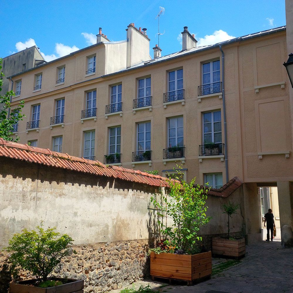 Cour intérieure ensoleillée jouxtant un immeuble d'appartements.