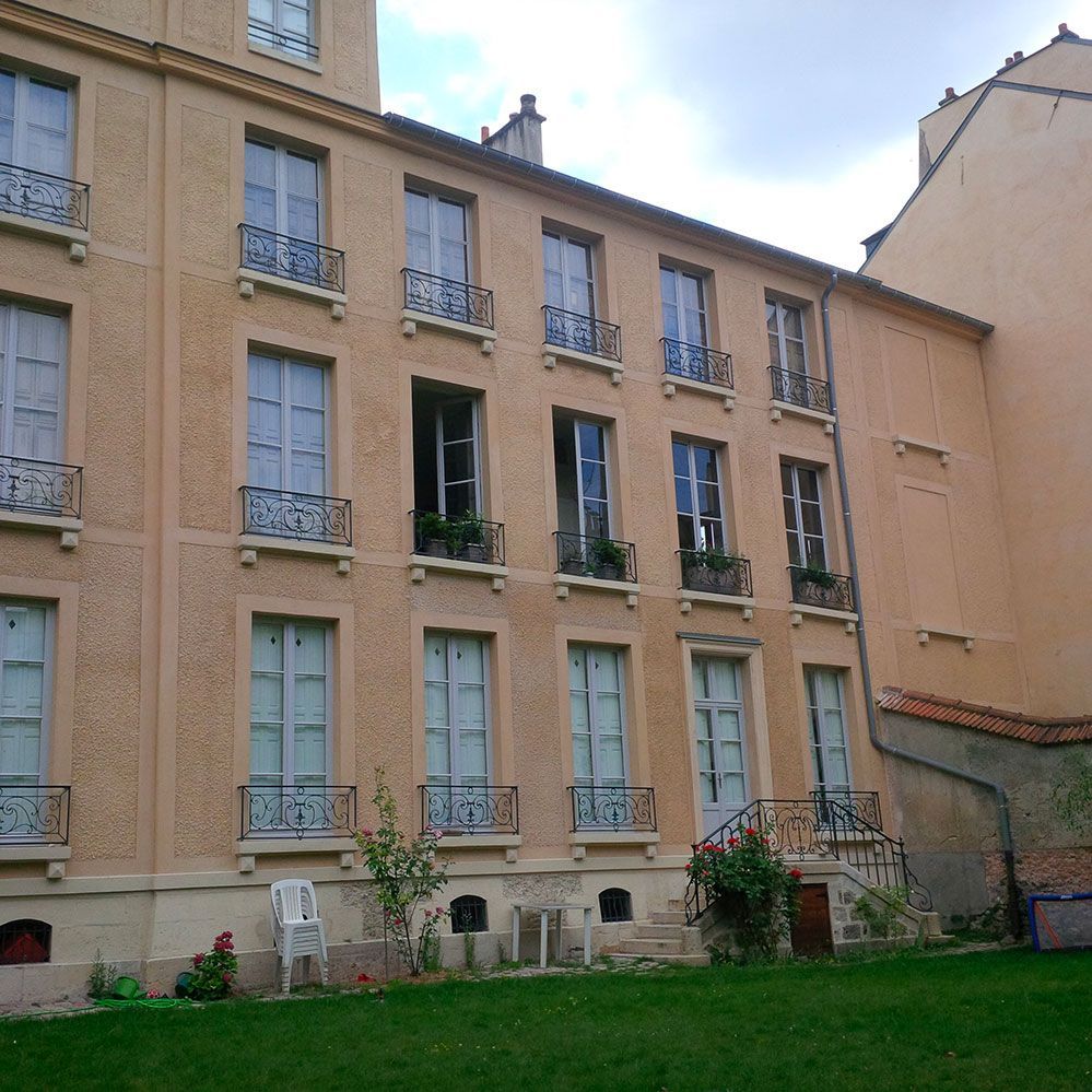 Immeuble d'appartements avec balcons et fenêtres, donnant sur un jardin