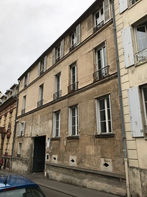 Rangée de vieux immeubles d'appartements dans une rue étroite sous un ciel nuageux