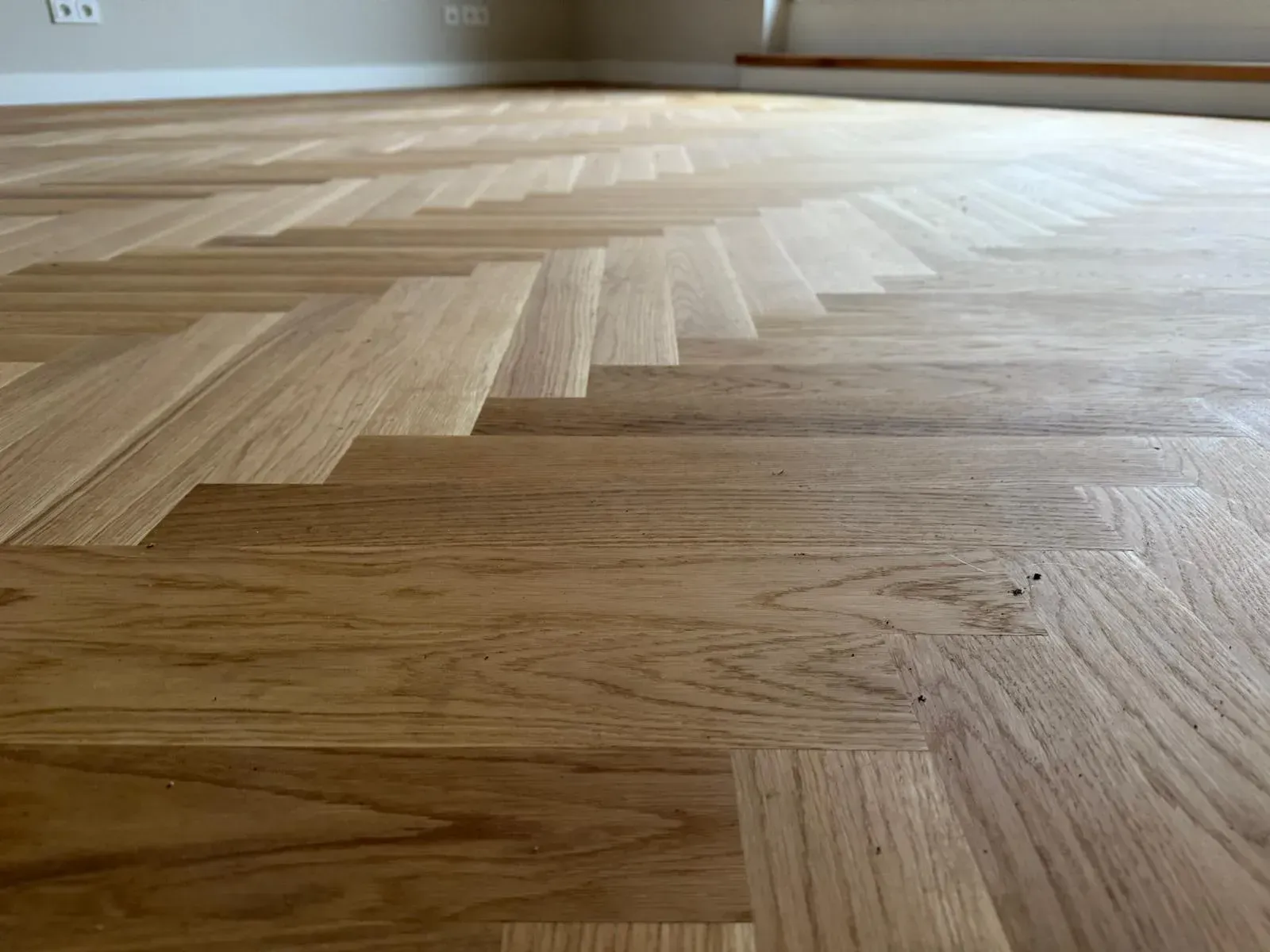 Eine Nahaufnahme eines Fischgrät-Holzbodens in einem Raum.