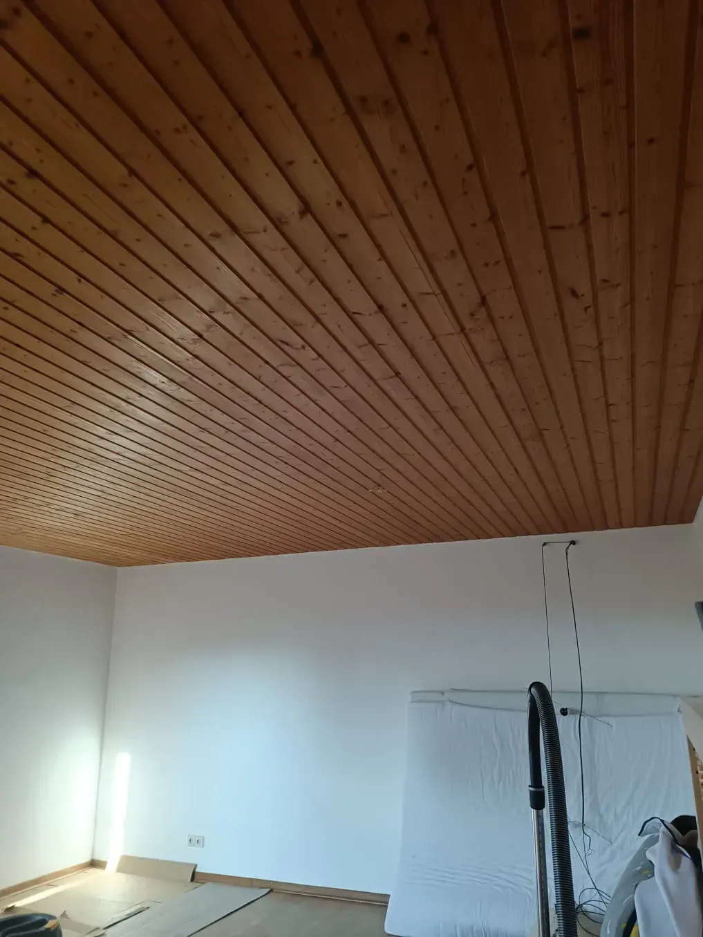 Ein Raum mit Holzdecke und weißen Wänden.