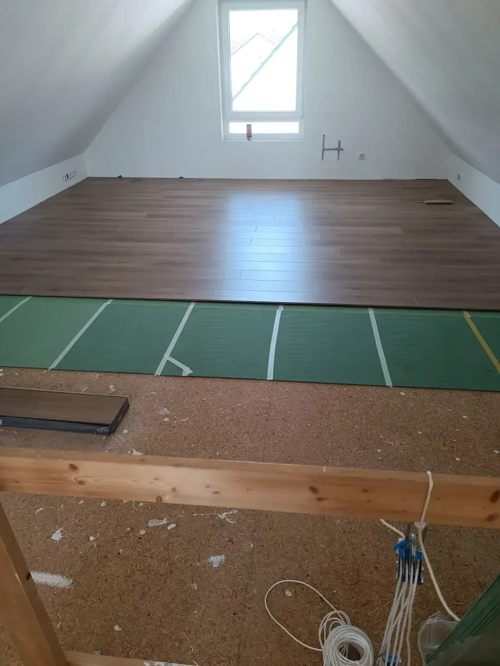 Ein Dachboden mit Holzboden und grüner Matte.