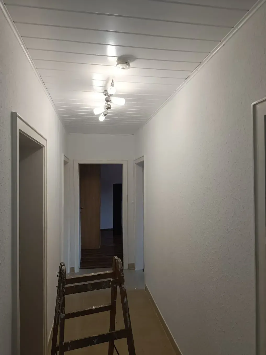 Ein langer Flur mit einer Leiter in der Mitte.