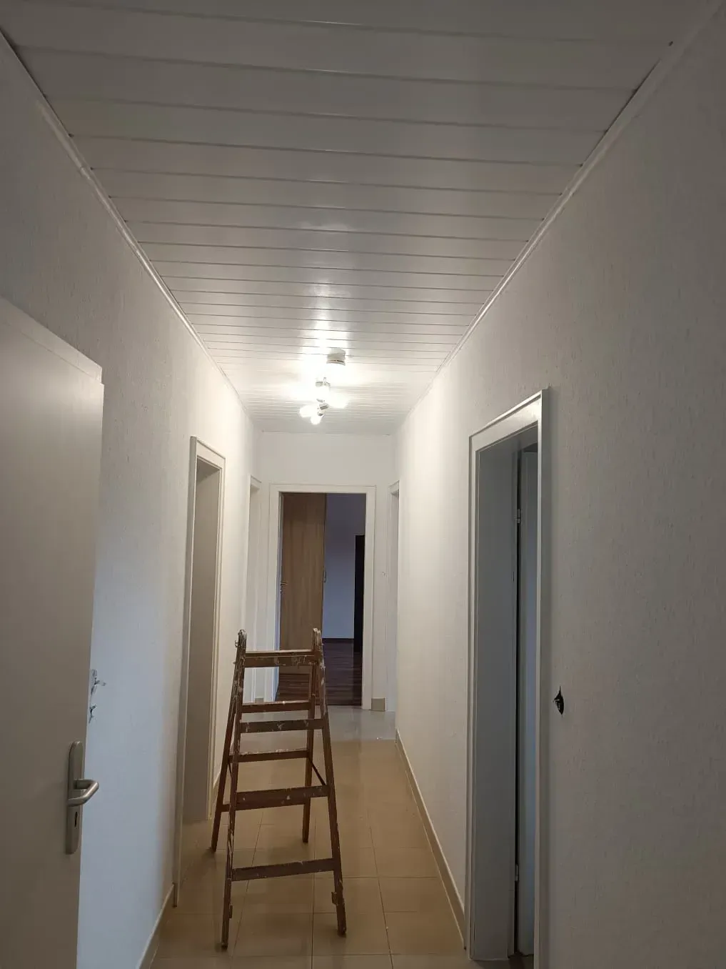 Ein langer Flur mit einer Leiter in der Mitte.