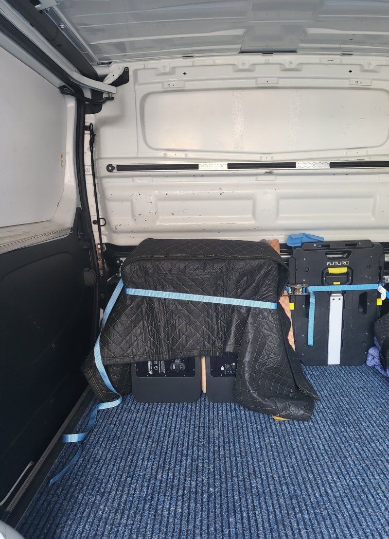 Die Rückseite eines weissen Lieferwagens mit blauem Teppich.