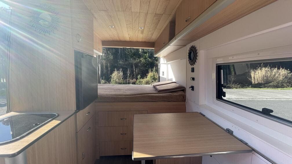 El interior de una furgoneta camper con una mesa y una cama.