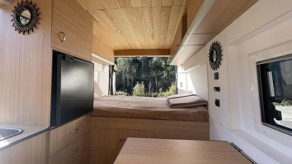 El interior de una furgoneta con una cama y una mesa.