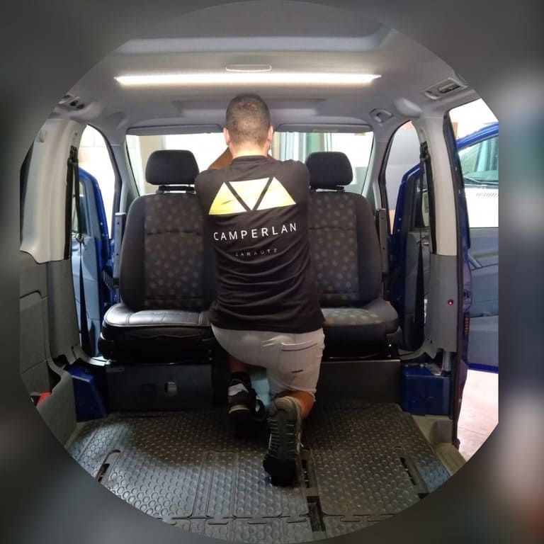 Un hombre está arrodillado en el asiento trasero de una autocaravana.