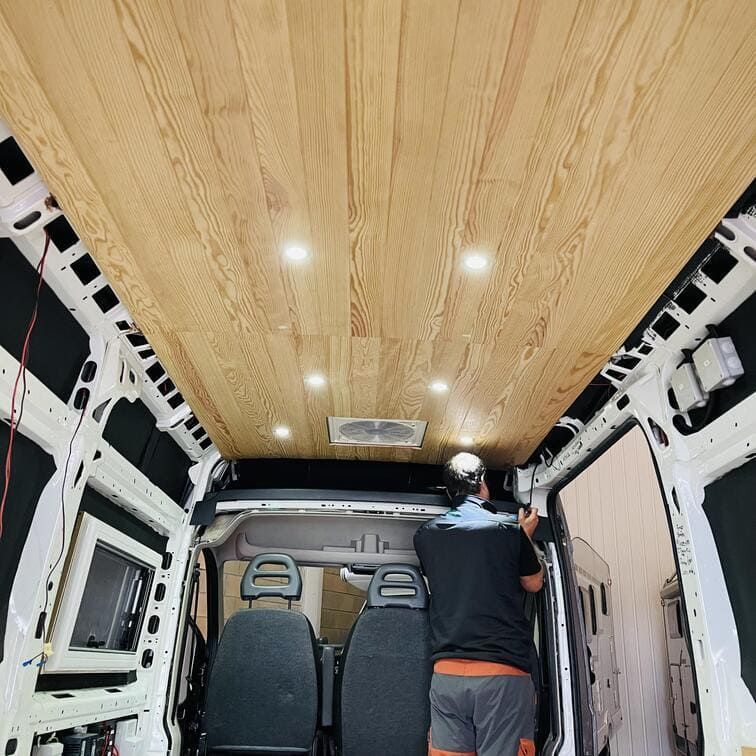 Un hombre está trabajando en el techo de una camioneta.