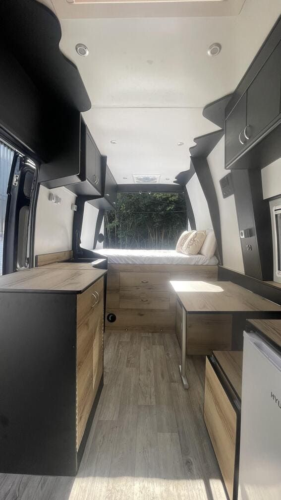 El interior de una furgoneta camper con una cama y una cocina.