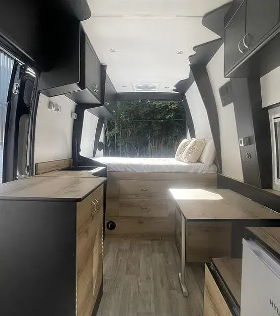El interior de una furgoneta con una cama y un escritorio.