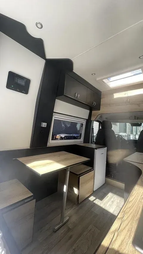 El interior de una furgoneta camper con una mesa y taburetes.