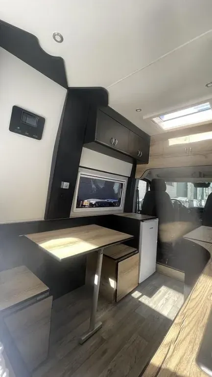 El interior de una furgoneta camper con una mesa y taburetes.