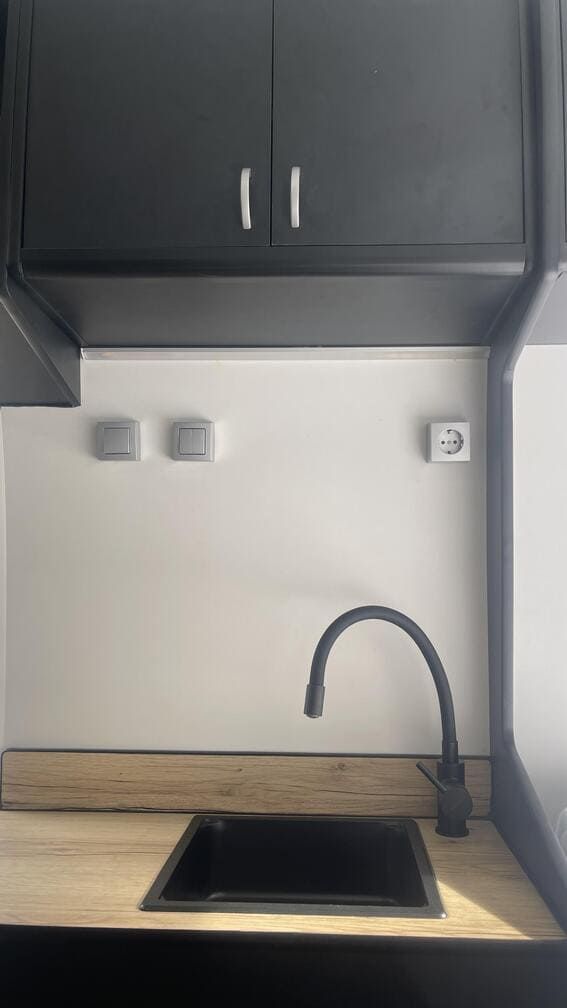 Un fregadero de cocina con grifo negro y gabinetes negros.