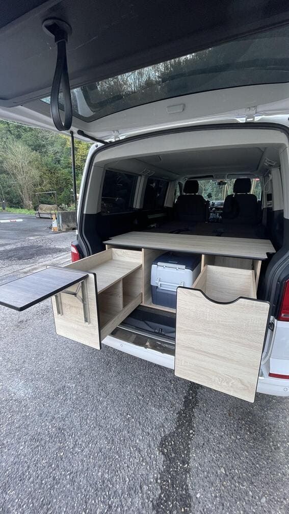 La parte trasera de una camioneta con una mesa y cajones dentro.