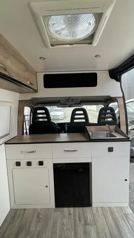 El interior de una furgoneta con cocina y ventilador en el techo.