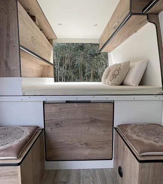 El interior de una furgoneta con una cama debajo.