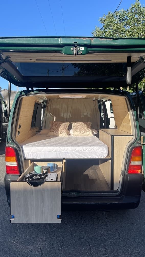 La parte trasera de una furgoneta con una cama en la parte trasera.
