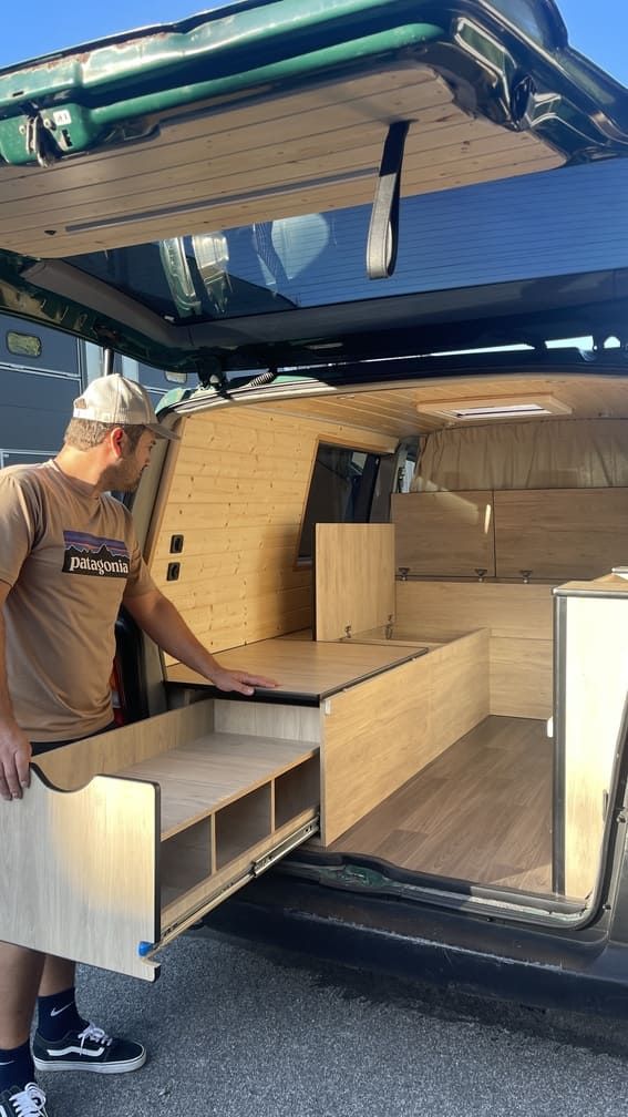 Un hombre está abriendo un cajón en la parte trasera de una camioneta.