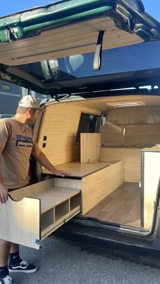 Un hombre está abriendo un cajón en la parte trasera de una camioneta.