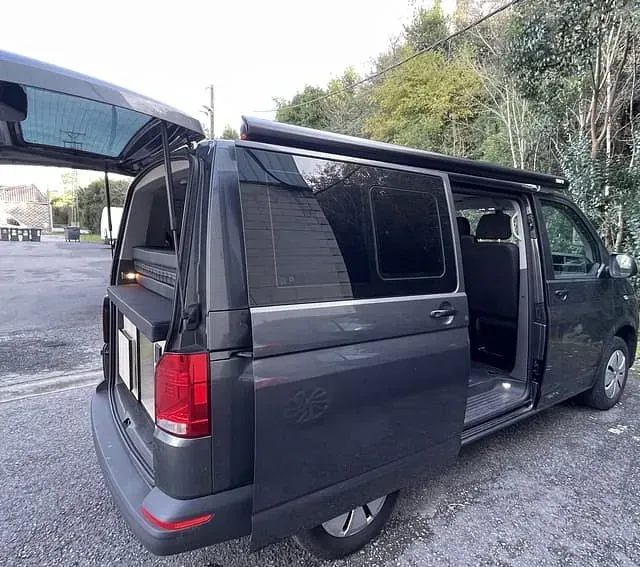 Una camioneta negra con las puertas abiertas está estacionada en un estacionamiento.