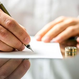 Una persona está escribiendo en un trozo de papel con una pluma fuente.