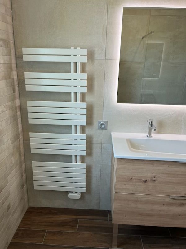 Une salle de bains avec un radiateur, une prise de courant, un évier et un miroir