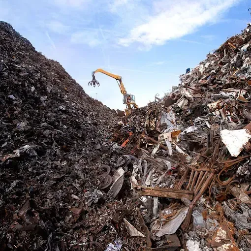 Excavadora amarilla y contenedor lleno de escombros en una obra de demolición.