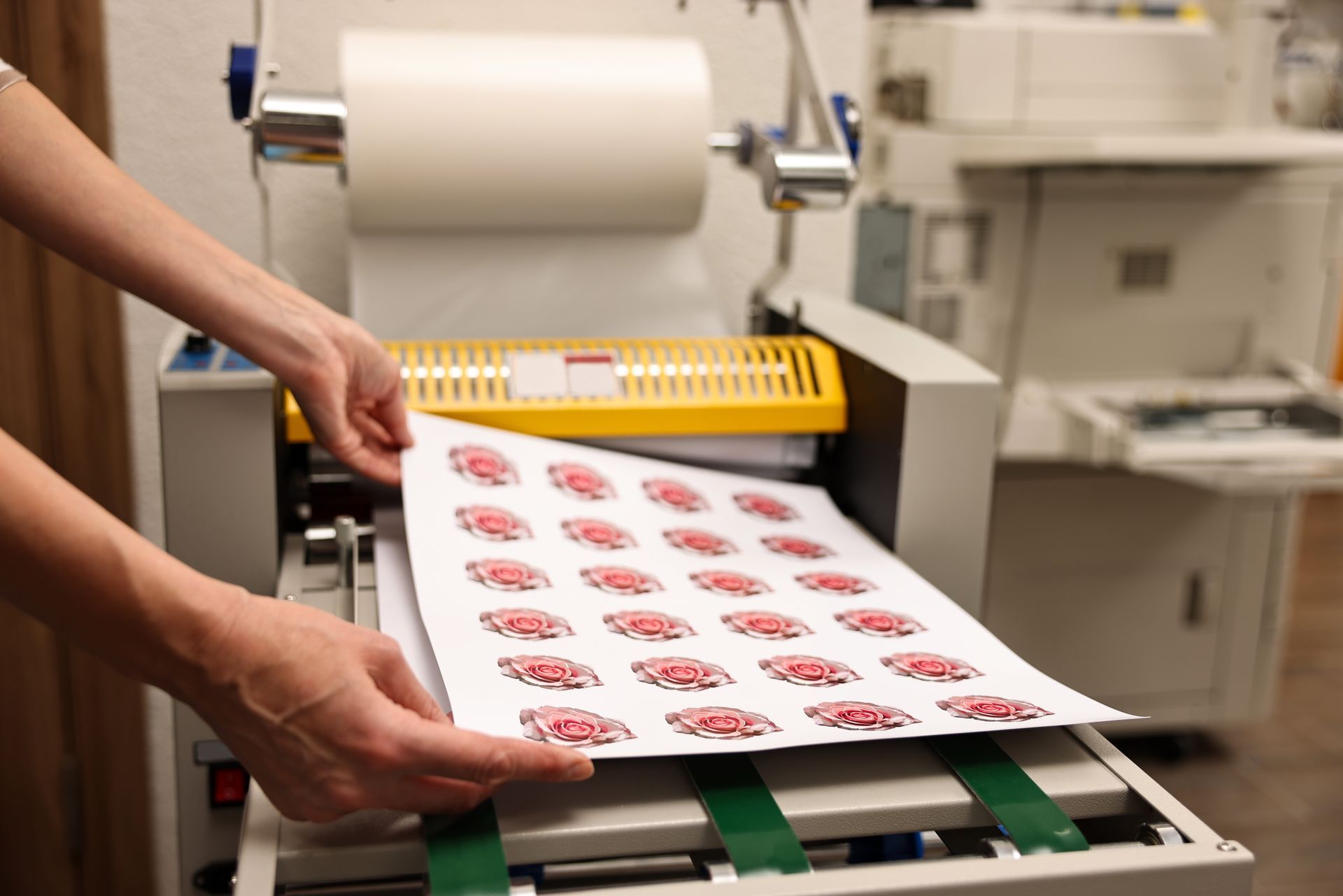 Des mains insèrent une feuille d’étiquettes imprimées dans une imprimante à étiquettes équipée de rouleaux verts