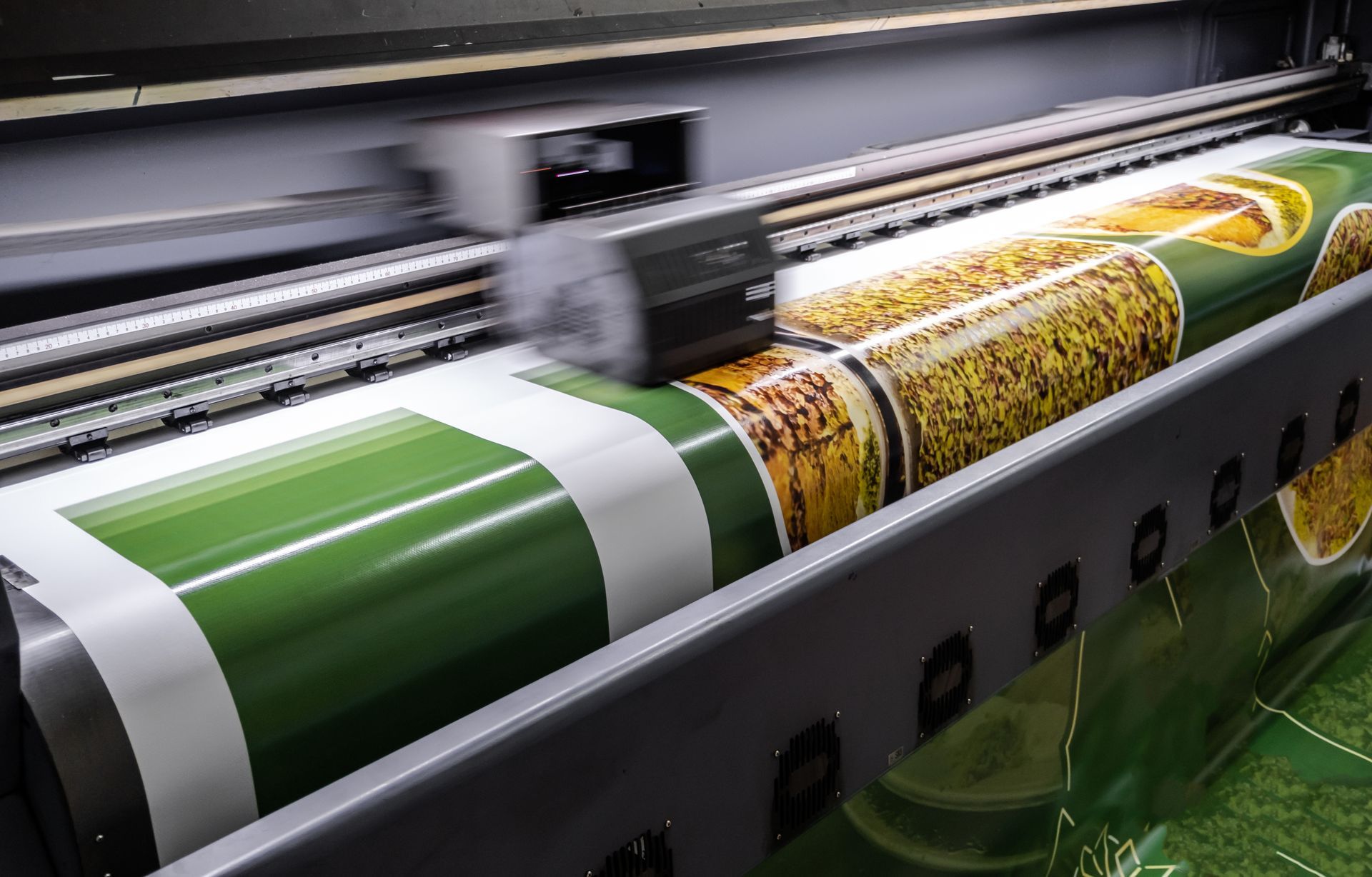 Imprimante grand format imprimant une banderole brillante verte et jaune sur un rouleau de matériau