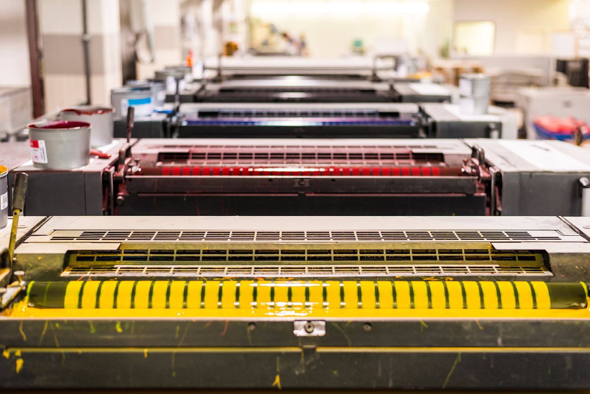Des rangées de presses d’imprimerie colorées dans un atelier industriel lumineux