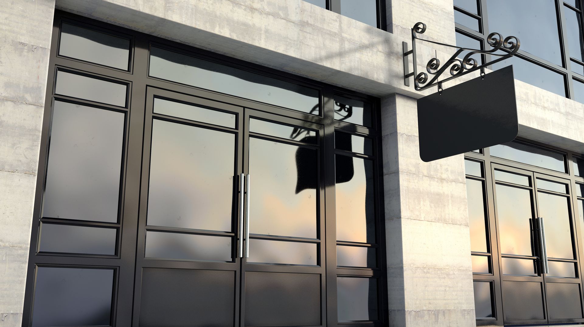 Vitrine baignée de soleil, avec des fenêtres en verre réfléchissant, une enseigne suspendue et une façade en pierre claire