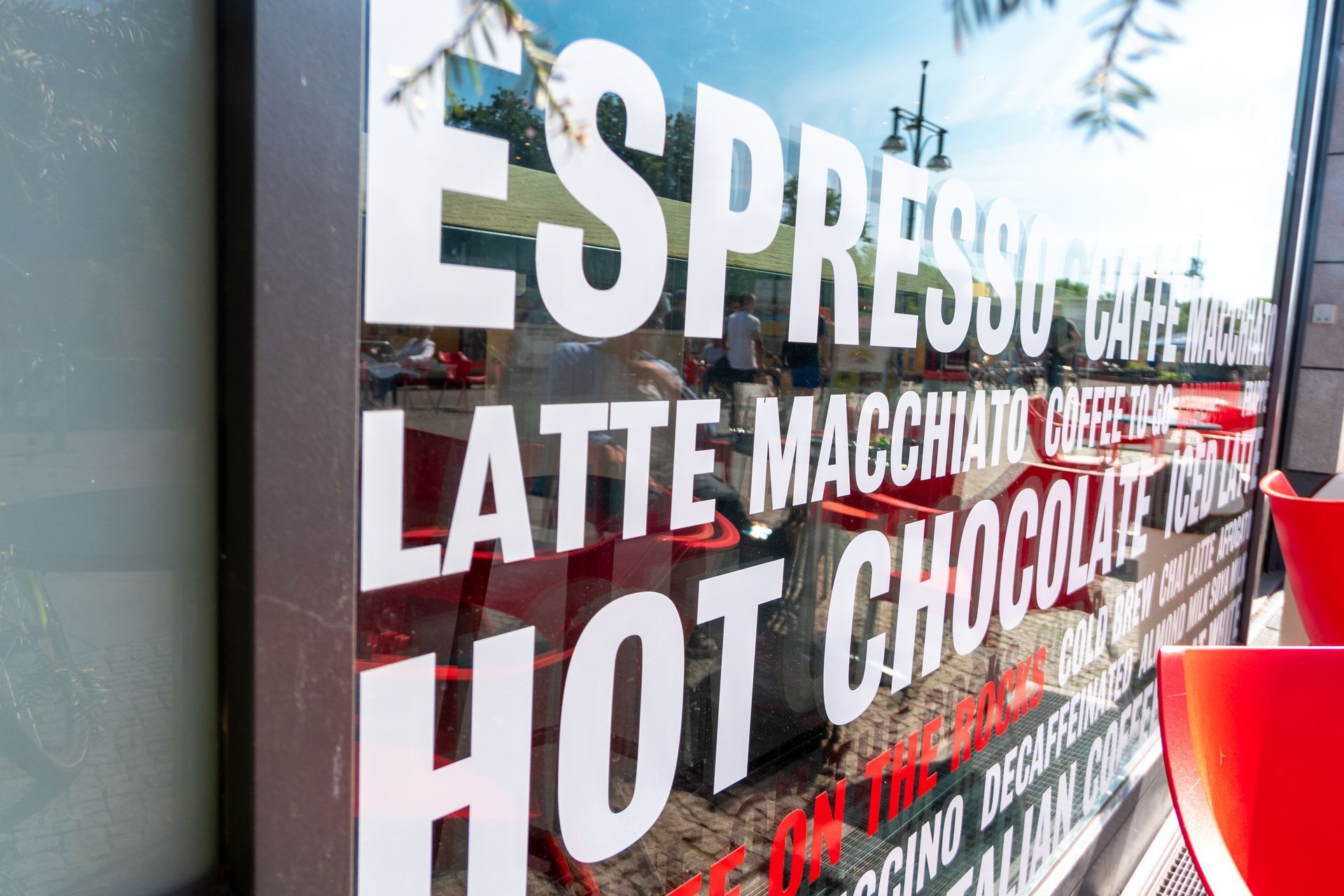 Enseigne de vitrine de café présentant un espresso, un latte macchiato et un chocolat chaud, en lettres blanches