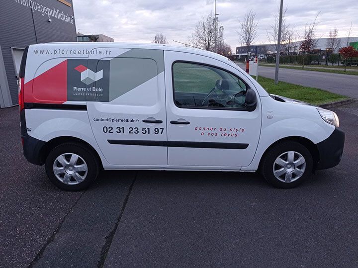 Fourgon de livraison blanc avec un logo rouge et gris, garé dans une rue, vu de côté