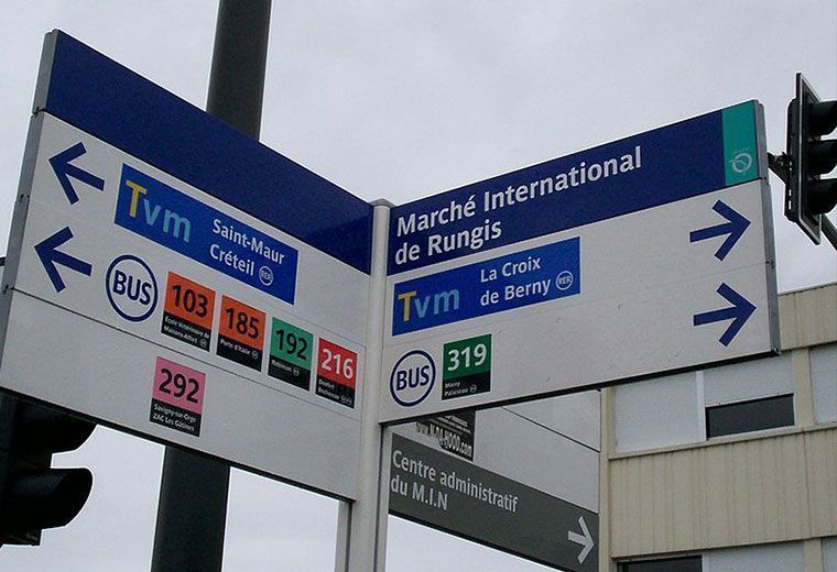 Panneaux routiers à un carrefour de Marseille, avec des indications bleues et blanches vers TVM et les lignes de bus.