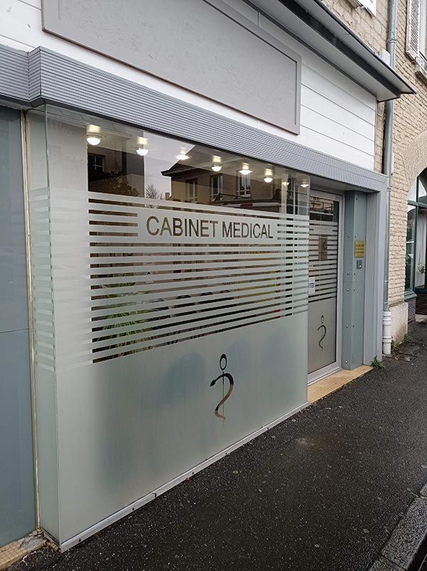 Vitrine en verre dépoli avec une entrée donnant sur le trottoir d’une rue pluvieuse