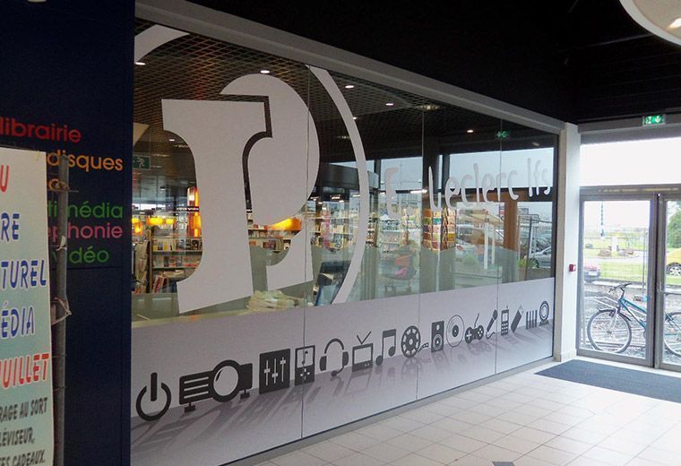 Vitrine en verre avec le logo Leclerc blanc et des pictogrammes d’accessibilité en bas