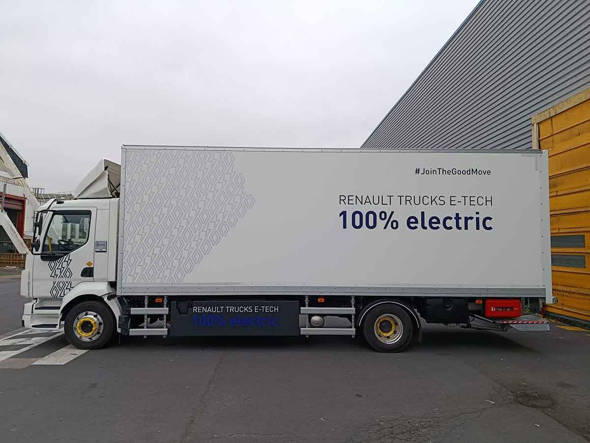 Camion de livraison électrique blanc garé à côté d’un bâtiment.