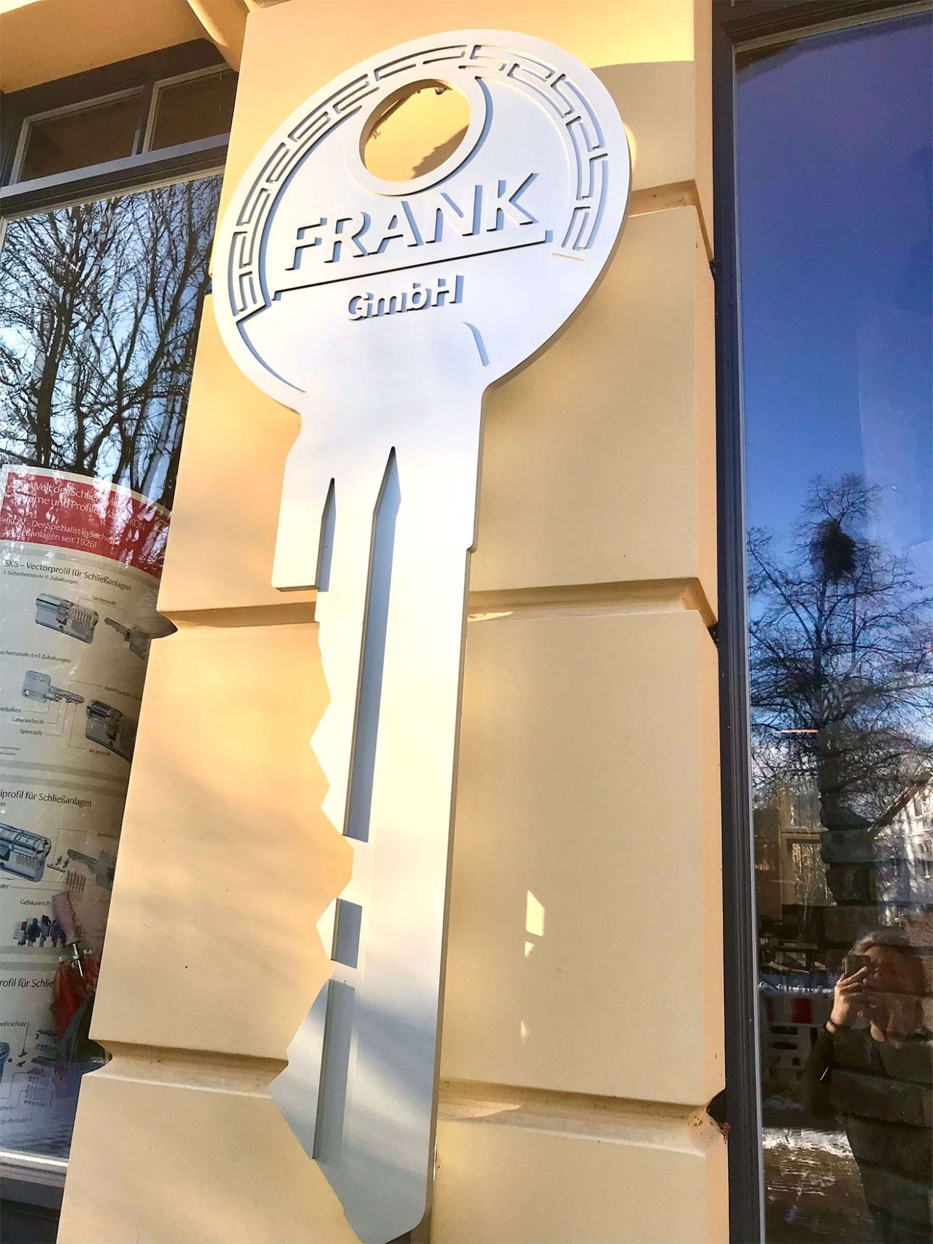 Großer silberner Schlüssel mit Firmenname an der Fassade des Ladengeschäfts