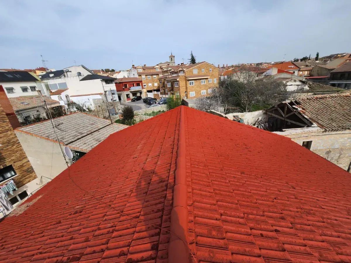 Una vista desde un ángulo elevado, mirando hacia abajo desde la cumbrera de un tejado de tejas rojas brillantes