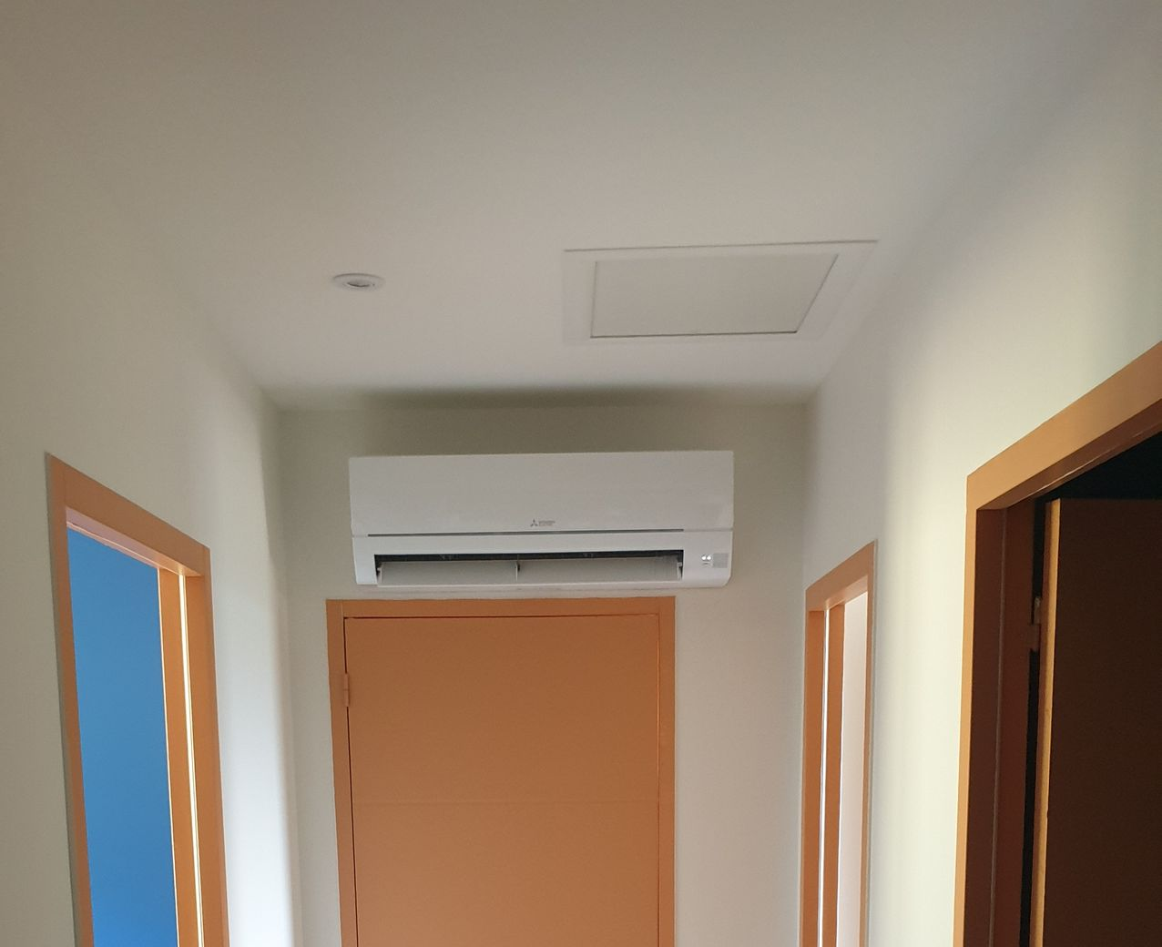 Un couloir avec portes et climatisation. Le plafond est doté d'une trappe.